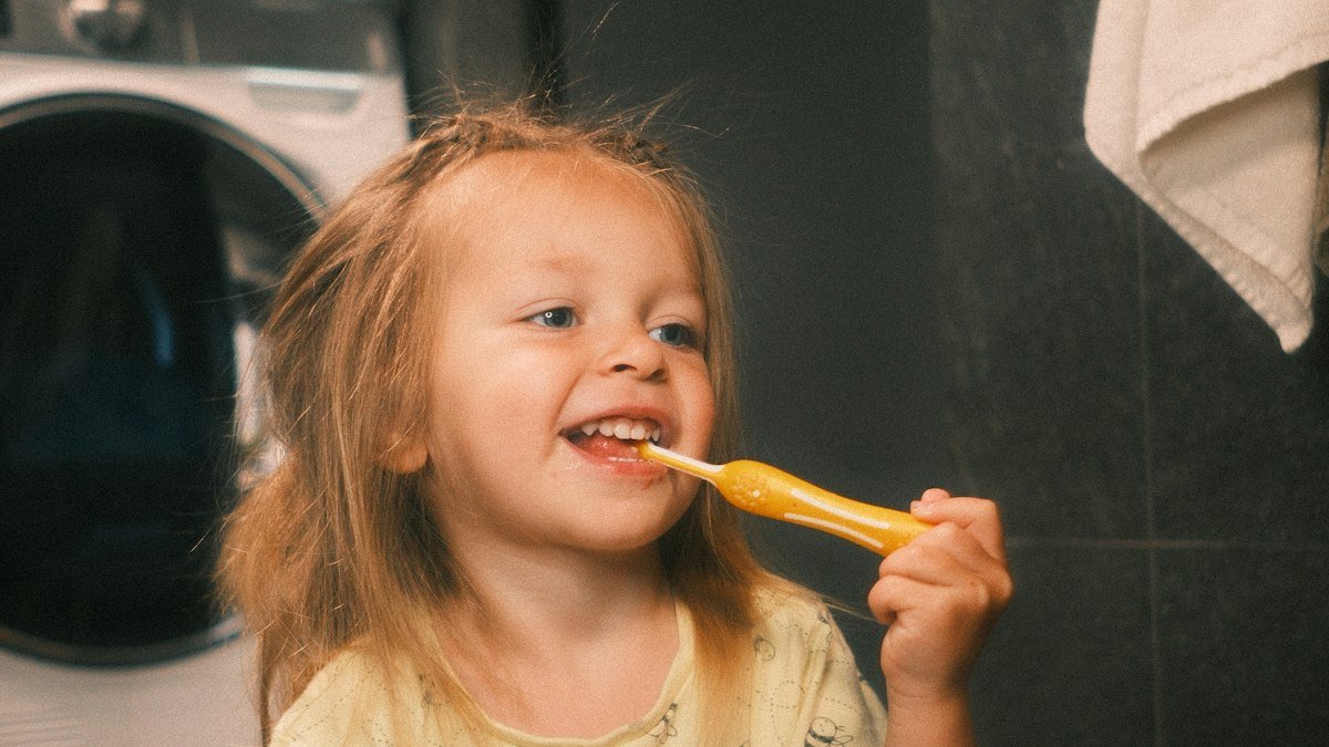 Young child happily brushing their teeth in the bathroom