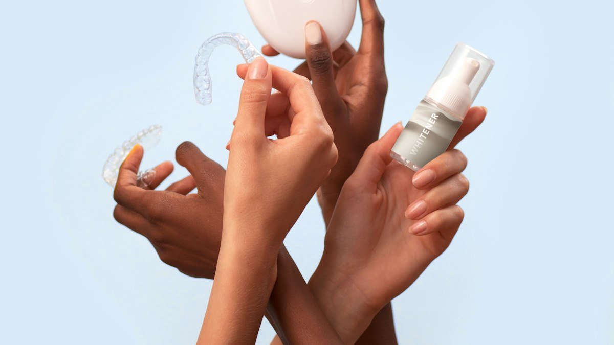 Hands holding clear custom trays with a storage case and a bottle of whitening gel for home teeth whitening