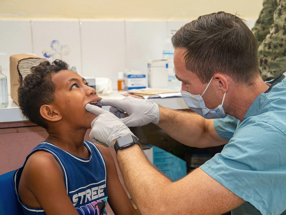 Dentist gently examining a young boy's teeth in the dental chair